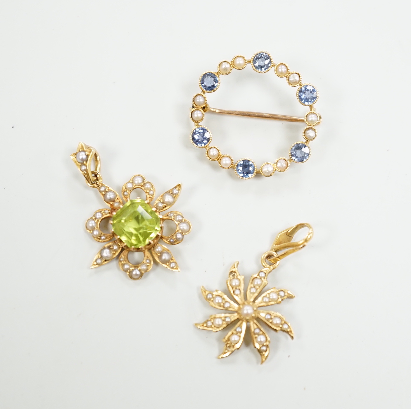 Two Edwardian 15ct and gem set pendants including peridot and seed pearl, 27mm and a similar 15ct and gem set open work circular brooch, gross weight 7 grams.